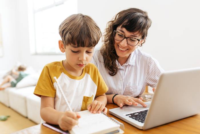 En kvinna och ett barn sitter vid en dator.